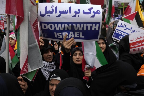 An Iranian demonstrator holds an anti-Israeli placard during a rally in front of the former U.S. Embassy in Tehran, Iran, marking 44th anniversary of the seizure of the embassy by militant Iranian students, Saturday, Nov. 4, 2023. (AP Photo/Vahid Salemi)