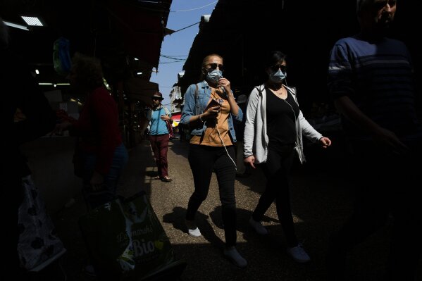 People wear face masks as they shop at a food market in Tel Aviv, Israel, Sunday, March 15, 2020.  ‏Israel has imposed a number of tough restrictions to slow the spread of the new coronavirus. Prime Minister Benjamin Netanyahu announced that schools, universities, restaurants and places of entertainment will be closed to stop the spread of the coronavirus. He also encouraged people not to go to their workplaces unless absolutely necessary.  (AP Photo/Oded Balilty)