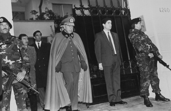 Gen. Augusto Pinochet exits his home, surrounded by security guards in Santiago, Chile, Sept. 7, 1986, the day after he survived an assassination attempt by the guerrilla group, Manuel Rodríguez Patriotic Front. (AP Photo/Marco Ugarte)