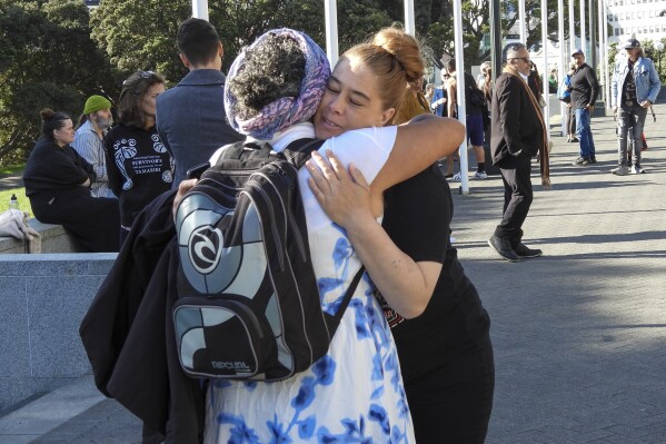 ADDS NAME - Jazmine Te Hiwi, right, embraces a friend as they arrive at Parliament House in Wellington, New Zealand ahead of the apology to the survivors of abuse in state, faith-based and foster care over a period of seven decades, Tuesday, Nov. 12, 2024. (AP Photo/Charlotte Graham-McLay )
