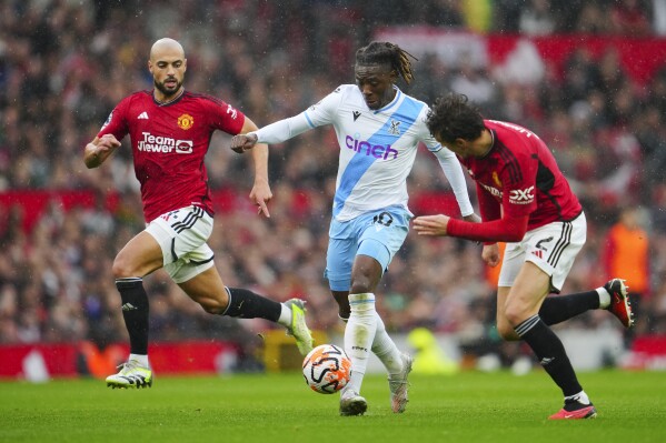 FILE - Crystal Palace's Eberechi Eze, center, dribbles the ball past Manchester United's Sofyan Amrabat, left, and Victor Lindelof during the English Premier League soccer match between Manchester United and Crystal Palace at the Old Trafford stadium stadium in Manchester, England, Saturday, Sept. 30, 2023. Crystal Palace midfielder Eberechi Eze has signed a contract extension to stay with the Premier League club until 2027. “I’m loving every moment,” the 25-year-old England international said in the club's announcement on Friday, Nov. 10, 2023. (AP Photo/Jon Super, File)
