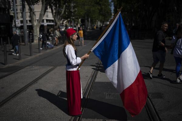 FILE - A woman dressed up as Marianne, a woman symbol of the French republic since the 1789 revolution, holds a French flag during a May Day demonstration in Marseille, southern France, May 1, 2022. Two landmark new studies in France are busting myths about immigration, at a time when xenophobic far-right discourse has gained ground, highlighting that immigration is melting into society but also pointing out persistent discrimination against some groups with immigrant backgrounds. (AP Photo/Daniel Cole, File)