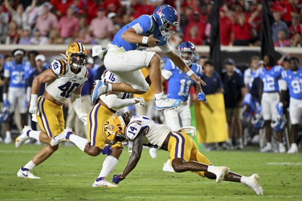 Mississippi quarterback Jaxson Dart, top, hurdles LSU safety Andre' Sam (14) during the second half of an NCAA college football game in Oxford, Miss., Saturday, Sept. 30, 2023. (AP Photo/Thomas Graning)