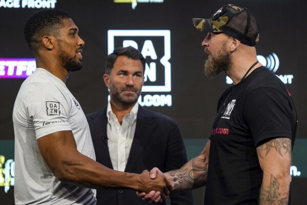 Britain's Anthony Joshua, left and Finland's Robert Helenius shake hands, with promoter Eddie Hearn at centre, during a press conference at the Pan Pacific London Hotel, London, Wednesday, Aug. 9, 2023. Joshua will face Helenius, at London's O2 Arena on Saturday after his heavyweight bout with Dillian Whyte was cancelled. (Nick Potts/PA via AP)