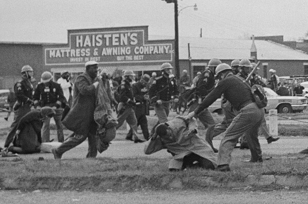 FILE - State troopers swing billy clubs to break up a civil rights voting march in Selma, Ala., March 7, 1965. Vice President Kamala Harris and Attorney General Merrick Garland are among those marking the 59th anniversary of Bloody Sunday in Selma, Alabama. The events mark law enforcement officers’ March 7, 1965, attack against demonstrators on the Edmund Pettus Bridge. (AP Photo, File)