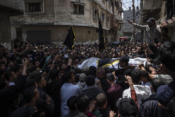 Mourners carry the bodies of Khalil Bahtini, the Islamic Jihad militant group's commander for the northern Gaza Strip, his wife and son, who were killed in an Israeli airstrike at their family home, during their funeral, in Gaza City, Tuesday, May 9, 2023. Bahtini was among three senior Islamic Jihad commanders killed in targeted airstrikes early Tuesday. Palestinian health officials said at least 10 others were killed, including wives of two of the militants, several of their children and others nearby. (AP Photo/Fatima Shbair)