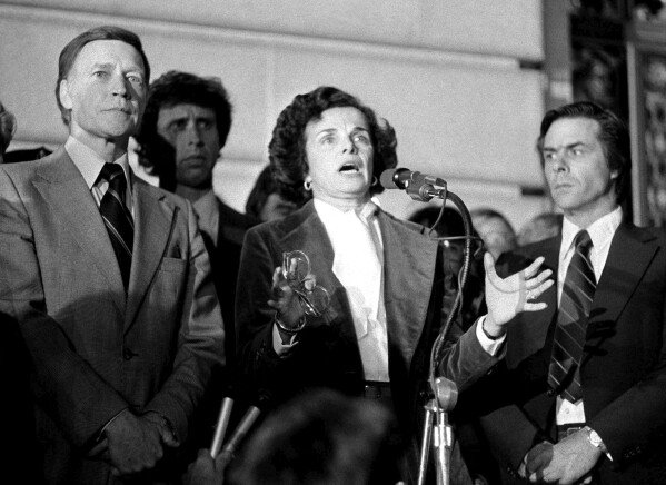 FILE - Acting Mayor Dianne Feinstein, with police Chief Charles Gain, at left, addresses the more than 25,000 people jammed around San Francisco's City Hall, Nov. 28, 1978, as residents staged a spontaneous memorial service for slain officials Mayor George Moscone and Supervisor Harvey Milk. Man at right is not identified. (AP Photo/File)