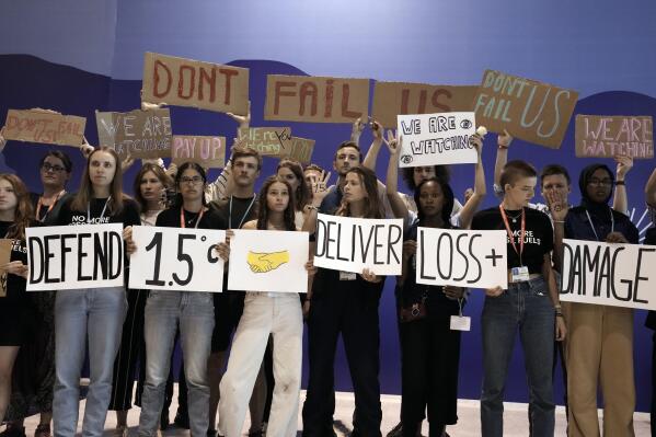 FILE - Youth activists hold signs encouraging world leaders to maintain policies that limit warming to 1.5 degrees Celsius since pre-industrial times and provide reparations for loss and damage at the COP27 U.N. Climate Summit, Nov. 19, 2022, in Sharm el-Sheikh, Egypt. The United Arab Emirates official tapped to head the next global climate summit, Sultan al-Jaber, pledged Thursday, June 8, 2023, to listen to young people demanding a place at the table when negotiators gather in the Gulf nation this fall. (AP Photo/Nariman El-Mofty, File)