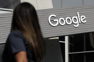 FILE - In this Sept. 24, 2019, file photo, a woman walks below a Google sign on the campus in Mountain View, Calif. On Wednesday, May 5, 2021, Google said that it expects about 20% of its workforce to still work remotely after the pandemic. In addition, some 60% will work a hybrid schedule that includes about three days in the office and two days wherever the employees work best. (AP Photo/Jeff Chiu, File)