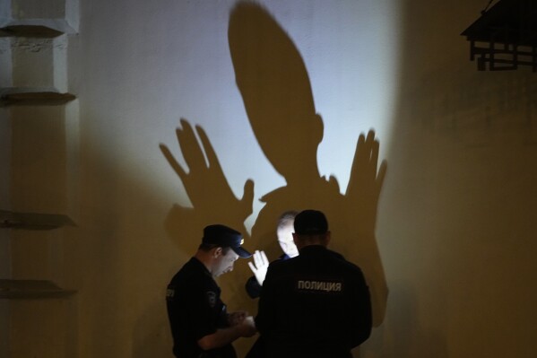 Police officers check documents of a man in central Moscow, Russia,  June 25, 2023. (AP Photo/Dmitri Lovetsky)