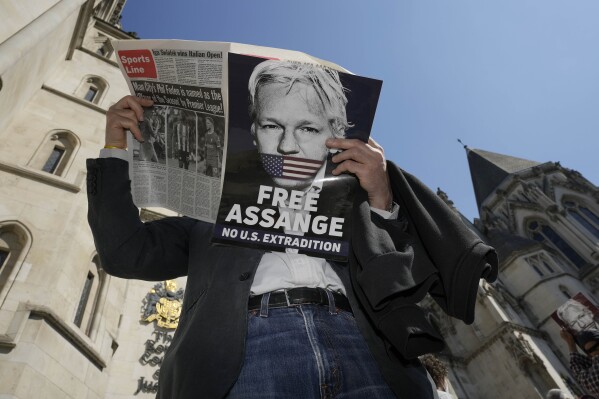 A protester reads a newspaper outside the High Court in London, Monday, May 20, 2024. A British court has ruled that WikiLeaks founder Julian Assange can appeal against an order that he be extradited to the U.S. on espionage charges.(AP Photo/Kin Cheung)