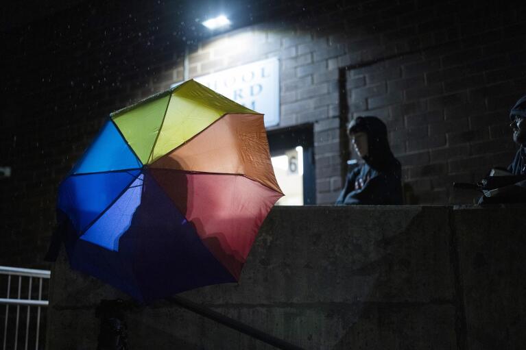 Central Bucks School District high school student Leo Burchell waits for a school board meeting to start, opening his rainbow colored umbrella as it begins to rain in Doylestown, Pa., on Tuesday, Nov. 15, 2022. “I don’t want my friends to be misgendered and deadnamed every single day just because they don’t want to come out to their parents,” Leo said. “It really just breaks my heart to know that some of my friends, you know, might not want to go to school anymore.” (AP Photo/Ryan Collerd)