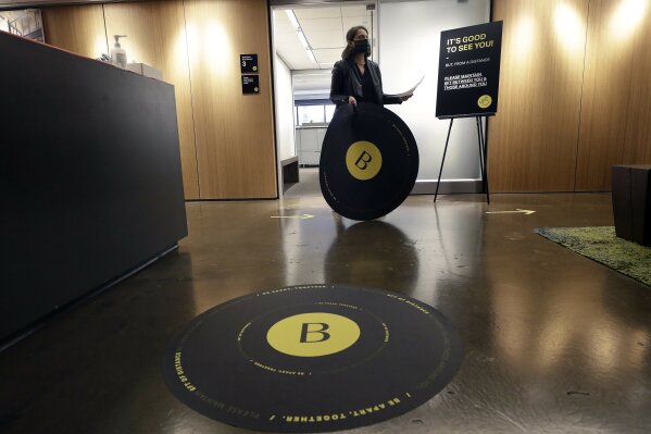 This Thursday, May 7, 2020, photo shows Vice President Rachel Zsembery at the design firm Bergmeyer working on the installation of safe distancing messages at the firms offices in Boston.  (AP Photo/Steven Senne)