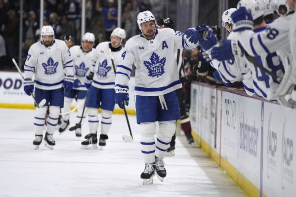 Toronto Maple Leafs center Auston Matthews (34) is congratulated after scoring his 50th goal of the season, against the Arizona Coyotes during the first period of an NHL hockey game Wednesday, Feb. 21, 2024, in Tempe, Ariz. (AP Photo/Rick Scuteri)