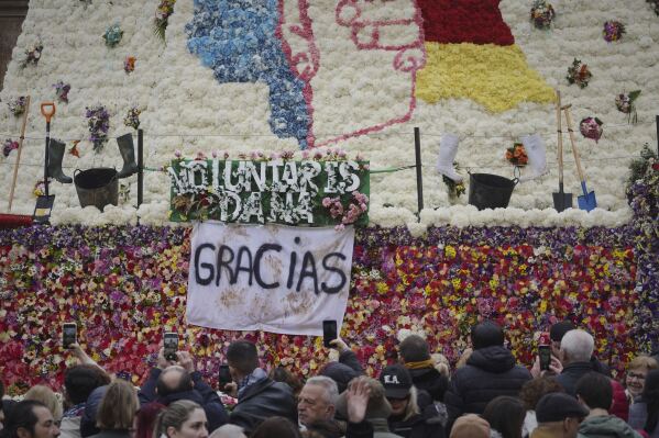 Assistants take photos at a figure of the Virgin decorated with a floral mantle, in honor of those who died during the past floods, during the Fallas festival in Valencia, Spain, on Wednesday, March 19, 2025. (AP Photo/Alberto Saiz)