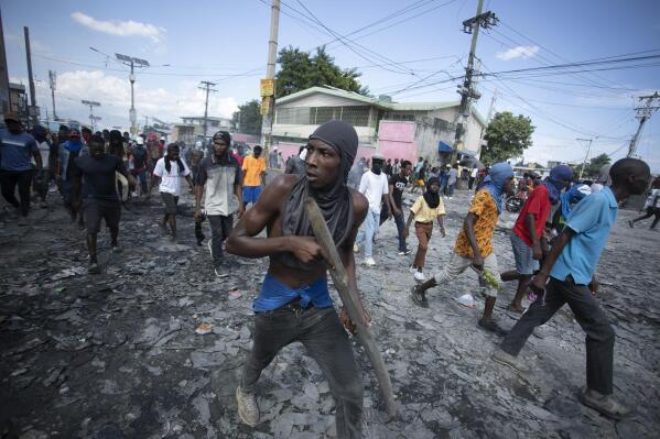 FILE - A protester carries a piece of wood simulating a weapon during a protest demanding the resignation of Prime Minister Ariel Henry, in the Petion-Ville area of Port-au-Prince, Haiti, Oct. 3, 2022. Haiti's government has agreed to request the help of international armed forces as gangs and protesters paralyze the country and basic supplies including fuel and water dwindle, a top ranking Haitian official told The Associated Press on Friday, Oct 7. (AP Photo/Odelyn Joseph, File)