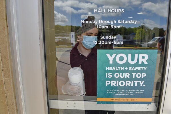 Kendall Ballew an employee of the Anderson Mall cleans the doors before the Anderson Mall opened to limited business after South Carolina Governor Henry McMaster eased restrictions due to coronavirus, Friday, April 24, 2020, in Anderson, S.C. (AP Photo/Richard Shiro)