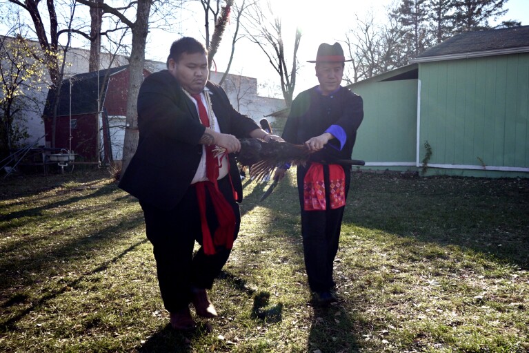 Anthony Yang, à gauche, et Nhia Neng Vang, à gauche, et Nhia Neng Vang marquent une ligne représentant la séparation de la nouvelle année de l'ancienne avec le sang d'un coq après un grand rituel dans le jardin de Nhia Neng Vang à St. Paul, Minnesota Le samedi 18 novembre 2023. Le Nouvel An est la célébration spirituelle traditionnelle la plus importante pour les réfugiés Hmong qui se sont installés ici après avoir fui au lendemain de la guerre du Vietnam.  (Photo AP/Mark Vancleave)