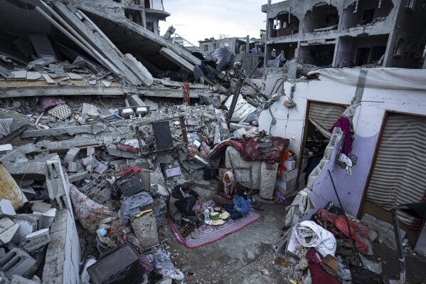 Members of the Al-Rabaya family break their fast during the Muslim holy month of Ramadan outside their destroyed home by the Israeli airstrikes in Rafah, Gaza Strip, Monday, March 18, 2024. (AP Photo/Fatima Shbair)