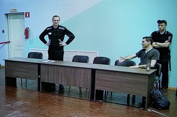 Russian opposition leader Alexei Navalny, left, and his associate Daniel Kholodny are seen at a TV screen as they appear in a video link provided by the Russian Federal Penitentiary Service, during a hearing in the colony, in Melekhovo, Vladimir region, about 260 kilometers (163 miles) northeast of Moscow, Russia, on Friday, Aug. 4, 2023. Navalny on Friday was convicted on extremism charges and sentenced to 19 years in prisons, in the harshest ruling against the imprisoned Kremlin critic to date. (AP Photo/Alexander Zemlianichenko)