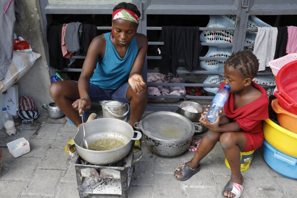A woman cooks at shelter for families displaced by gang violence, in Port-au-Prince, Haiti, Friday, March 8, 2024. The violence as anti-government gangs battle police in the streets has crippled Haiti’s economy and made it extremely difficult for many of the country's most vulnerable to feed themselves.(AP Photo/Odelyn Joseph)