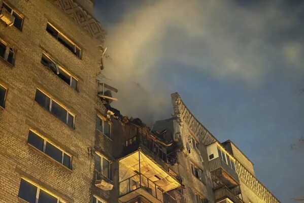 In this photo provided by the Ukrainian Emergency Service, smoke rises behind an apartment building damaged in Russia's Shahed-type drone hit in Dnipro, Ukraine, Friday, Feb. 23, 2024. (Ukrainian Emergency Service via AP)