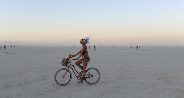  A woman rides a bicycle on the playa after sunset at the Burning Man festival in Gerlach, Nev., Friday, Aug. 30, 2013.(Andy Barron/The Reno Gazette-Journal via AP, File)