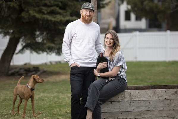 Aaron and Carrie Friesen pose for a photo with chickens and their dog Georgia in the back yard of their home in Boise, Idaho, on April 12, 2023. The couple and their three children recently moved to Idaho from the Bluffton, S.C., area. Americans are segregating by their politics at a rapid clip, helping fuel the greatest divide between the states in modern history. (AP Photo/Kyle Green)