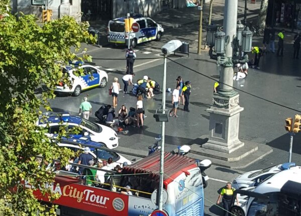 
              Injured are helped by responders as a tour bus passes by after a white van jumped the sidewalk in the historic Las Ramblas district of Barcelona, Spain, crashing into a summer crowd of residents and tourists Thursday, Aug. 17, 2017.   According to witnesses the white van swerved from side to side as it drove into tourists and residents. (Daniel Vil via AP)
            