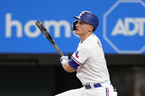 Texas Rangers' Cory Seager follows through on a run-scoring single in the second inning of a baseball game against the Chicago White Sox, Wednesday, Aug. 2, 2023, in Arlington, Texas. Sam Huff scored on the hit. (AP Photo/Tony Gutierrez)