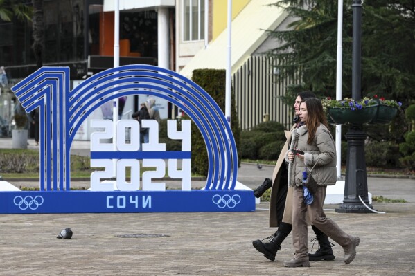 Two women walk past a sign marking the 10th anniversary of the Sochi 2014 Olympic and Paralympic Winter Games in central Sochi, Russia, on Saturday, Feb. 3, 2024. Sochi has continued to serve as a venue for winter sports and some international sporting events until they were pulled from Russia in response to the conflict in Ukraine. (AP Photo)