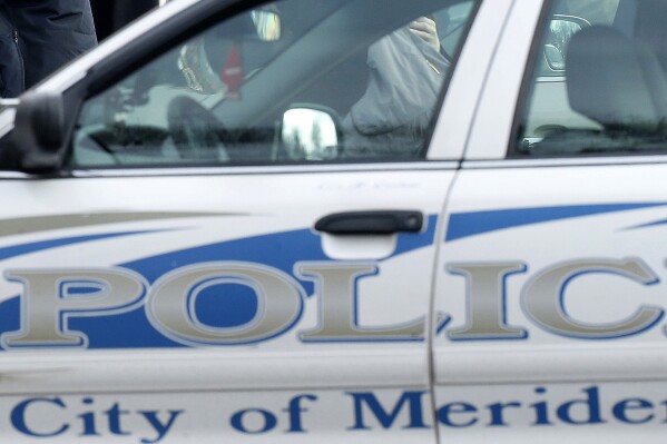 FILE - A city of Meriden, Conn., police vehicle is seen outside of St. Rose of Lima Roman Catholic Church, Dec. 18, 2012, in Newtown, Conn. Meriden Police Cpl. Allen Ganter, who was caught on camera punching a motorist who honked at him, got suspended for five days and charged with assault but has been allowed to keep his job. (AP Photo/Julio Cortez, File)