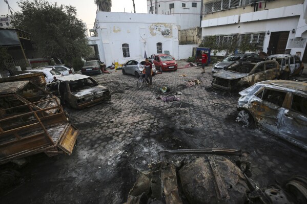 FILE - Men look over the site of a deadly explosion at Al-Ahli Hospital in Gaza City, Wednesday, Oct. 18, 2023. This photo and others taken the morning after the explosion show no evidence of a large crater at the impact site that would be consistent with a large bomb such as those dropped by Israeli aircraft in other recent strikes. (AP Photo/Abed Khaled, File)