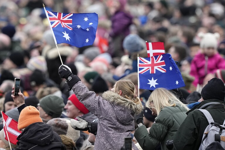 Ein Zuschauer schwenkt australische Flaggen, während sie am Sonntag, den 14. Januar 2024, vor Schloss Christiansborg in Kopenhagen, Dänemark, auf die Ankunft der dänischen Königsfamilie warten. Königin Margrethe II. wird die erste Königin von Dänemark sein, die seit fast 900 Jahren abdankt, wenn sie den Thron übergibt an ihren Sohn, der zum König Frederik gekrönt wird. .  (AP Photo/Martin Meissner)