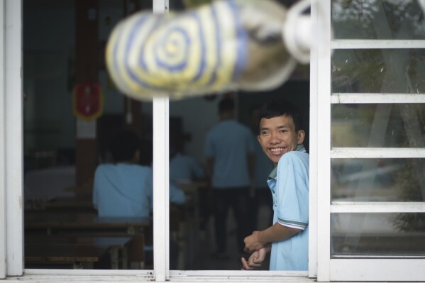 Một cậu bé mỉm cười nhìn ra ngoài cửa sổ tại một ngôi trường dành cho nạn nhân chất độc da cam ở Đà Nẵng, Việt Nam, ngày 7 tháng 3 năm 2025. (Ảnh AP/Aniruddha Ghosal)