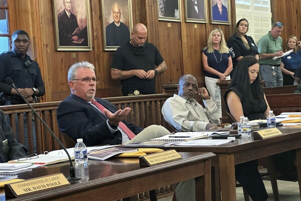 McIntosh County Commission Chairman David Stevens, left, speaks Tuesday, Sept. 12, 2023, at a table alongside fellow Commissioners Roger Lotson, center, and Kate Pontello Karwacki, right, at a meeting in Darien, Ga. Commissioners approved zoning changes that double the size of homes allowed in the tiny Gullah-Geechee community of Hogg Hummock on Sapelo Island. Hogg Hummock residents and landowners, who are descended from enslaved people, fear the changes will increase property values and taxes, potentially forcing them to sell their land. (AP Photo/Russ Bynum)