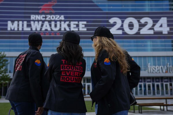 People gather outside the Fiserv Forum watching news ahead of the 2024 Republican National Convention, Saturday, July 13, 2024, in Milwaukee. Former president Donald Trump was whisked off the stage at a rally in Butler, Pennsylvania after apparent gunshots rang through the crowd. (AP Photo/Matt Rourke)