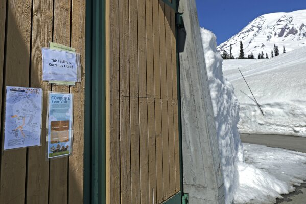 Signs offer tips for preventing the spread of the new coronavirus, as well as the closed status of the Henry M. Jackson Visitor Center, at Paradise, Wednesday, March 18, 2020, at Mount Rainier National Park in Washington state. Most national parks are remaining open during the outbreak of the new coronavirus, but many are closing visitor centers, shuttles, lodges and restaurants in hopes of containing the spread of the coronavirus. (AP Photo/Ted S. Warren)