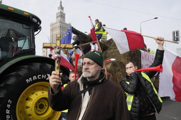 Polish farmers with national flags and angry slogans written on boards, protest against European Union green policies that trim their production and against cheap grain and other food imports from Ukraine, in Warsaw, Poland, on Tuesday, Feb. 27, 2024. Farmers have been protesting for weeks across the EU. (AP Photo/Czarek Sokolowski)