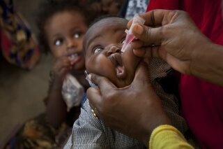 FILE - In this Wednesday April 24, 2013 file photo, a Somali child receives a polio vaccine, at the Medina Maternal Child Health center in Mogadishu, Somalia. The World Health Organization says a new polio outbreak in Sudan is linked to an ongoing vaccine-sparked epidemic in Chad - a week after the U.N. health agency declared the African continent free of wild polio virus. In a statement Wednesday, Sept. 2020, WHO said two children in Sudan - one from South Darfur state and the other from Gedarif state, close to the border with Ethiopia and Eritrea - were paralyzed in March and April. Both had been recently vaccinated against polio. (AP Photo/Ben Curtis, file)