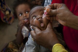 FILE - In this Wednesday April 24, 2013 file photo, a Somali child receives a polio vaccine, at the Medina Maternal Child Health center in Mogadishu, Somalia. The World Health Organization says a new polio outbreak in Sudan is linked to an ongoing  vaccine-sparked epidemic in Chad - a week after the U.N. health agency declared the African continent free of wild polio virus. In a statement Wednesday, Sept. 2020, WHO said two children in Sudan - one from South Darfur state and the other from Gedarif state, close to the border with Ethiopia and Eritrea - were paralyzed in March and April. Both had been recently vaccinated against polio. (AP Photo/Ben Curtis, file)