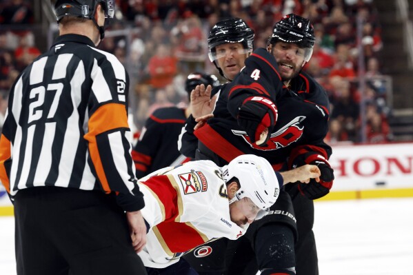 Carolina Hurricanes' Shayne Gostisbehere (4) hits Florida Panthers' Brad Marchand, left, during an altercation at the third period of Game 1 of the NHL hockey Stanley Cup Eastern Conference finals in Raleigh, N.C., Tuesday, May 20, 2025. (AP Photo/Karl DeBlaker)