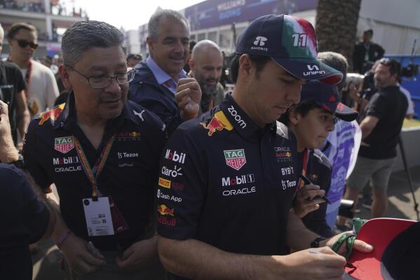 Red Bull driver Sergio Perez, of Mexico, signs an autograph during the Formula One Mexico Grand Prix at the Hermanos Rodriguez racetrack in Mexico City, Friday, Oct. 28, 2022. (AP Photo/Fernando Llano)