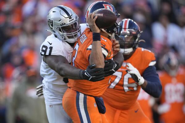 Denver Broncos quarterback Russell Wilson, middle, is hit by Las Vegas Raiders defensive tackle Bilal Nichols (91) while passing during the first half of an NFL football game in Denver, Sunday, Nov. 20, 2022. (AP Photo/David Zalubowski)