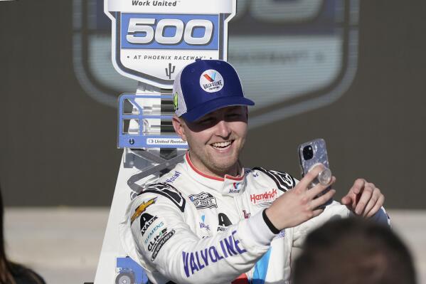 William Byron takes a photo with his trophy after winning a NASCAR Cup Series auto race at Phoenix Raceway, Sunday, March 12, 2023, in Avondale, Ariz. (AP Photo/Darryl Webb)