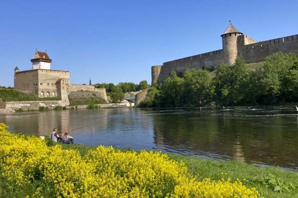 FILE - Men are seen fishing near the fortresses of Narva, left, in Estonia, and Ivangorod, right, in Russia, on Wednesday, May 24, 2023. The two countries took radically different paths after the Soviet Union's collapse, and an Associated Press correspondent who was in Moscow for almost all of Vladimir Putin’s rule until earlier this year has watched Russia’s steps forward as well as its retreat into isolation. Now assigned to Estonia, he tries to parse Russia's lost promise. (AP Photo/Jim Heintz, File)