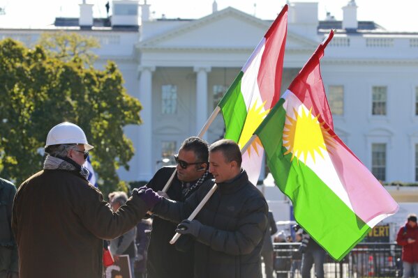 A small group of demonstrators, Diyar, right, and Dijon, center, greet a friend as they hold Kurdistan flags in front of the White House as thy protest the visit of Turkish President Recep Tayyip Erdogan at Lafayette Square in Wednesday, Nov. 13, 2019, in Washington. (AP Photo/Steve Helber)