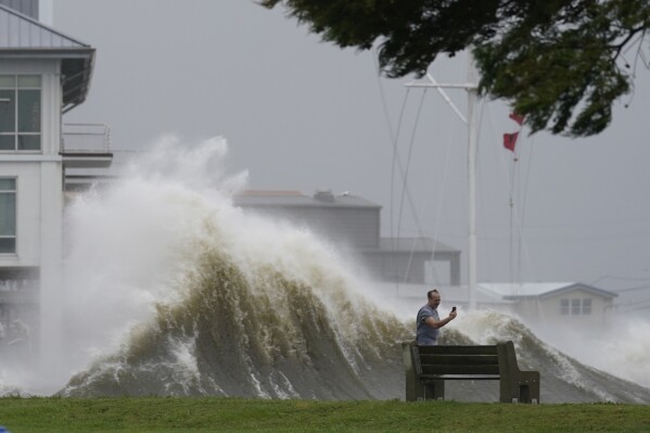 FILE - A man takes pictures of high waves along the shore of Lake Pontchartrain as Hurricane Ida nears, Aug. 29, 2021, in New Orleans. (AP Photo/Gerald Herbert, File)