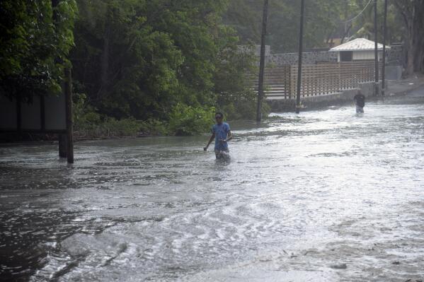 A man walks through a flooded road in the coast of the Indian Ocean Island of Mauritius Monday Feb. 20, 2023. Forecasts say Tropical Cyclone Freddy is increasing in intensity and is expected to pass north of the Indian Ocean island nation of Mauritius and make landfall in central Madagascar Tuesday evening.It's feared that up to 2.2 million people, mostly in Madagascar, will be impacted by storm surges and flooding, according to the Global Disaster Alert and Coordination System.(AP Photo/L'express Maurice)