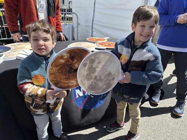 Gabriel Kauffman, 4, and his brother, Theodore, 6, demonstrate a total solar eclipse at a NASA booth at the Great Lakes Science Center in Cleveland, on Sunday, April 7, 2024. They live in Baltimore and came to the Cleveland area to see the eclipse with relatives. (AP Photo/Stephanie Nano)